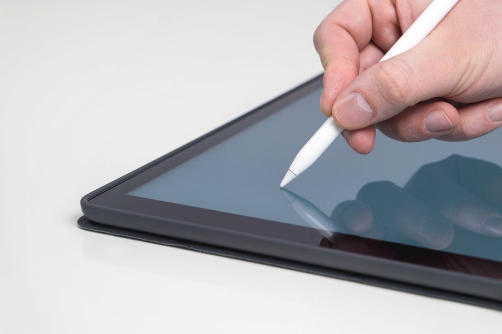 Uma mão segurando uma caneta digital e fazendo anotações sobre marcenaria moderna em um tablet