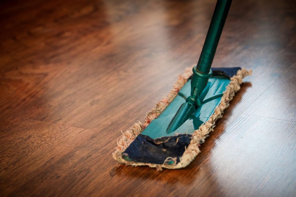 Um esfregão sobre um chão de madeira, remetendo a como limpar madeira.