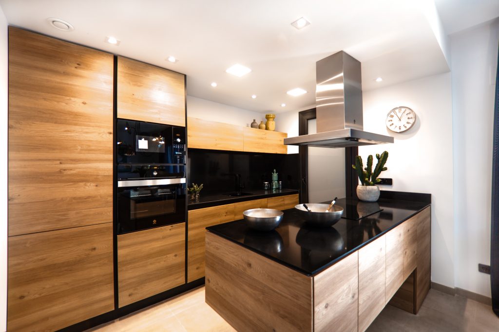 Uma cozinha que exibe diferentes tons de madeira combinados, desde a geladeira até a bancada principal