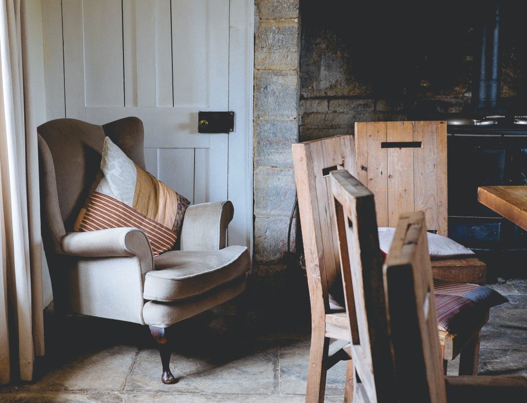 Um espaço com algumas cadeiras e uma mesa feitas com madeira de estilo rústico. As paredes também são de tijolos