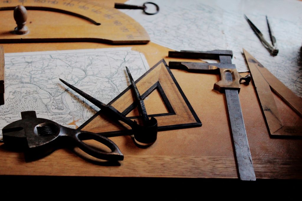 Algumas ferramentas de medição sobre uma mesa, como compassos e esquadros. 