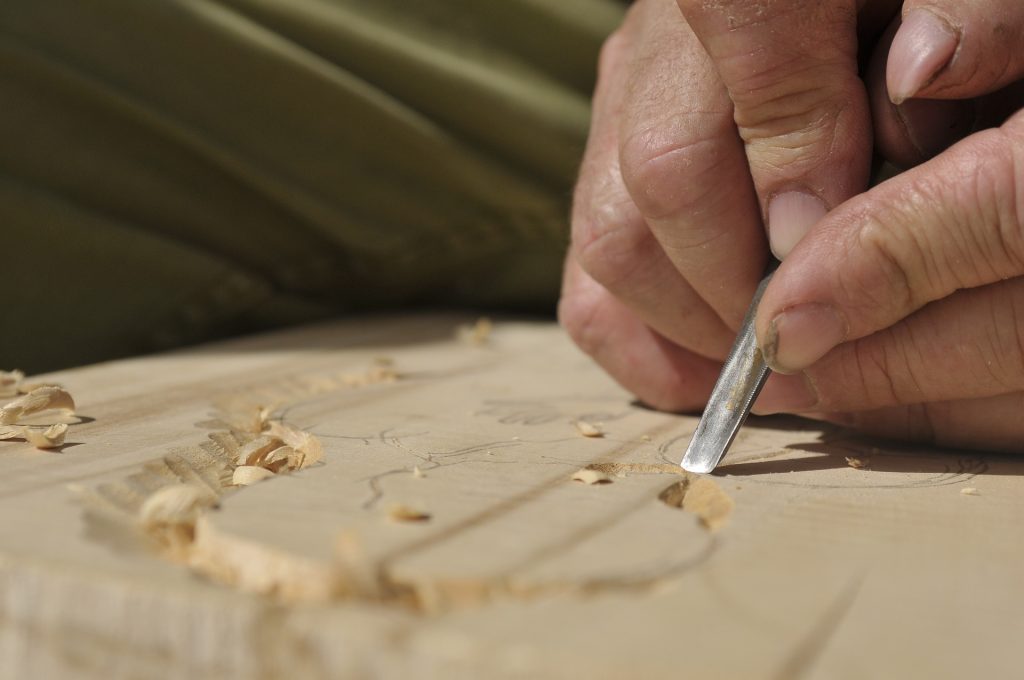 Uma mão utilizando um formão para entalhar madeira. No meu próprio negócio de marcenaria, essa é uma ferramenta que não pode faltar.
