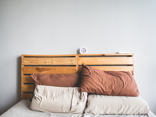 Uma cama de casal com uma cabeceira de pallet e travesseiros.