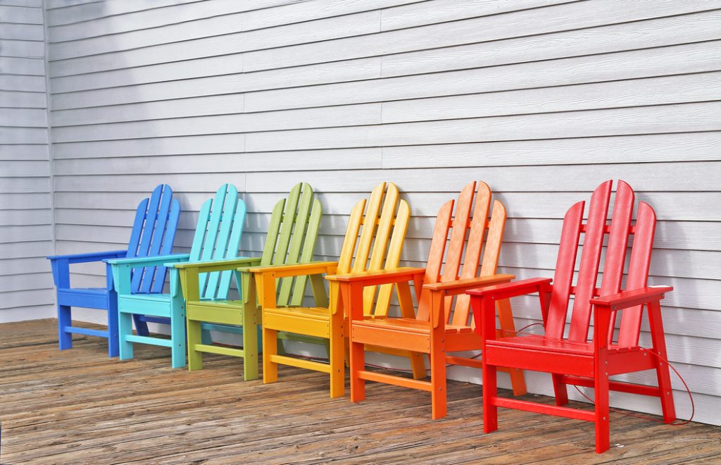 Cadeiras de madeira pintadas em diversas cores para decoração da área externa.