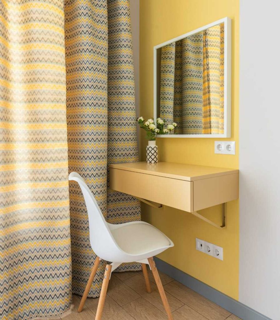 Cor amarela na decoração do espaço da penteadeira de um cômodo.